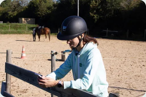 Une cavalière consulte l'application Appaloo au bord de la carrière